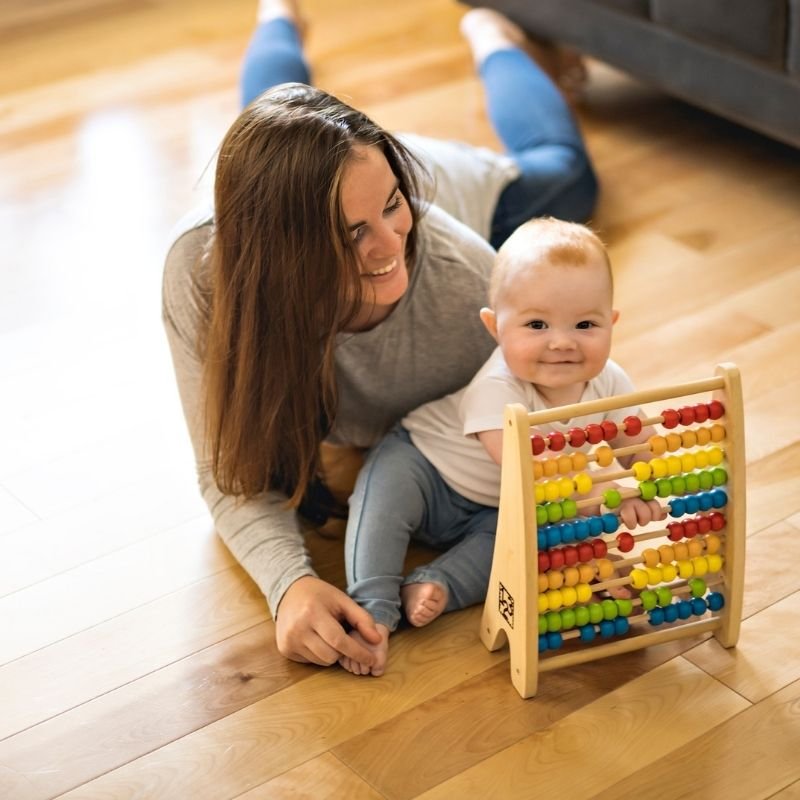 A woman and a baby joyfully playing together with a colorful abacus, fostering early learning and interaction.