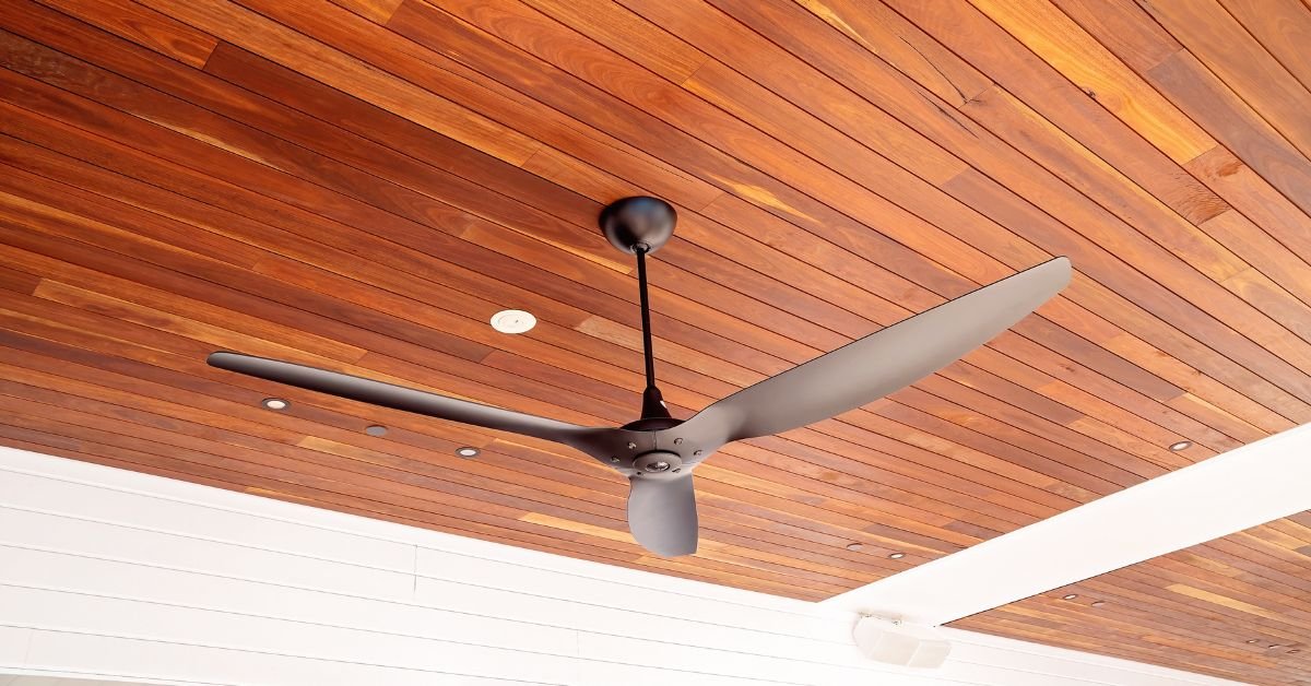 A ceiling fan mounted on a wooden ceiling in a cozy room, showcasing its blades and light fixture.