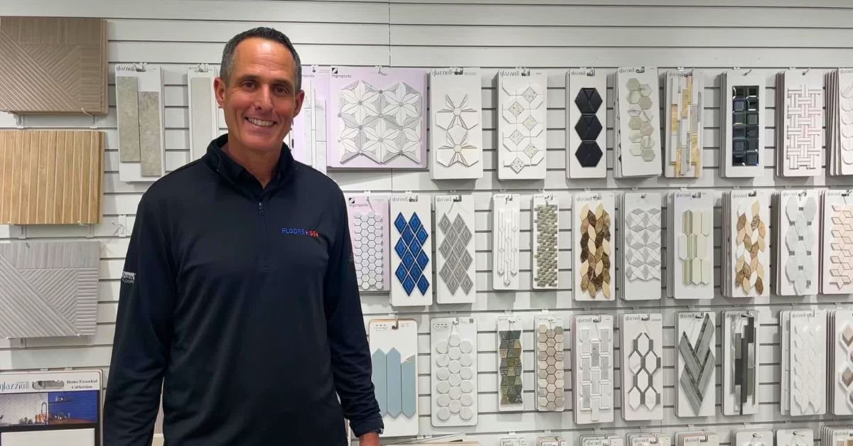 Scott Erlbaum stands in front of a colorful wall of tiles, showcasing various patterns and designs.