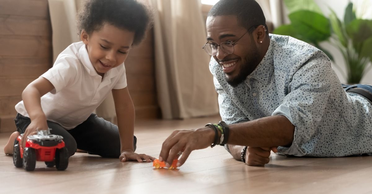 A man and a child joyfully playing together with colorful toy cars on a bright, sunny day.