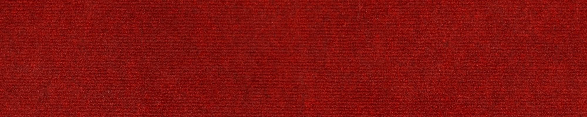 Bold red carpet serves as the background, accented by a small area of white for visual interest.