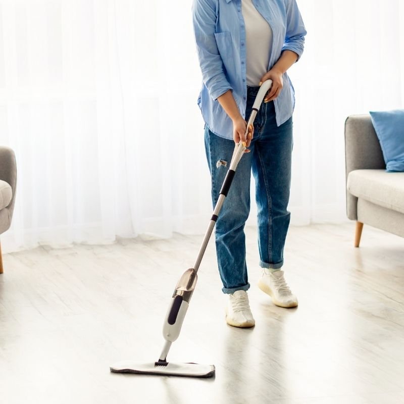 A woman vacuums the floor of a room, ensuring it is clean and tidy.